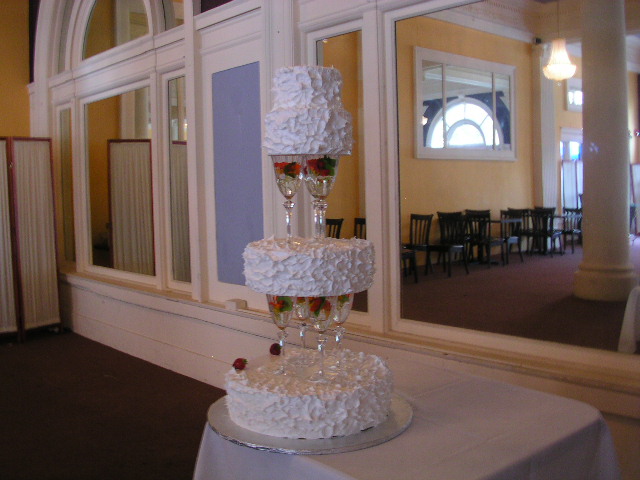 そう な ケーキ を 重ね て いき ます 白い ケーキ に ワイングラス の 中 の 花 が とても 鮮やか です